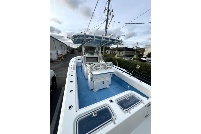 Slide: The Image of 2023 Contender 30 ST boat with blue deck and center console, parked outdoors. - 2