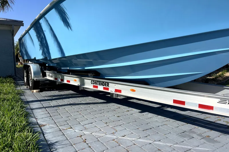 Slide: The Image of 2023 Contender 30 ST boat on trailer, parked on paved driveway under clear blue sky. - 44