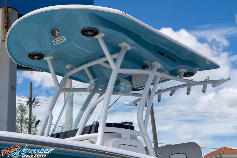 Slide: The Image of 2021 Sea Fox 228 Commander boat with blue T-top and rod holders against a cloudy sky. - 10