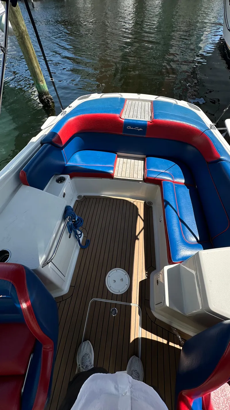 Slide: The Image of 2009 Chris-Craft Corsair 25 boat with red and blue seating, docked on water. - 13