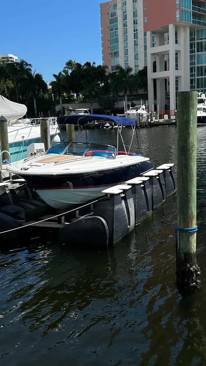 Slide: The Image of 2009 Chris-Craft Corsair 25 docked in a marina with modern buildings in the background. - 4