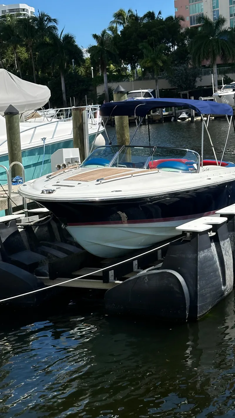 Slide: The Image of 2009 Chris-Craft Corsair 25 docked in a marina, surrounded by water and other boats. - 5