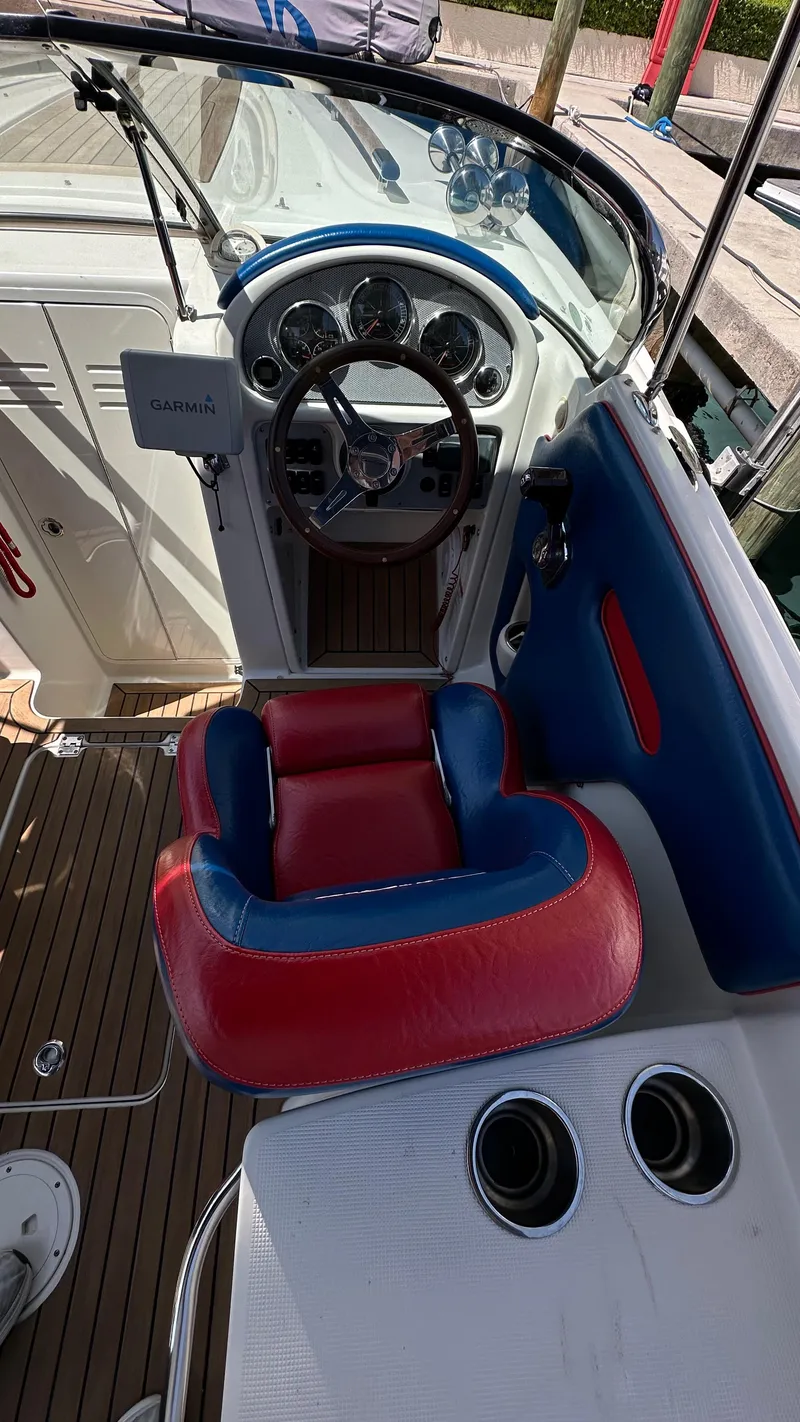 Slide: The Image of 2009 Chris-Craft Corsair 25 boat interior with red and blue seating, steering wheel, and dashboard. - 8