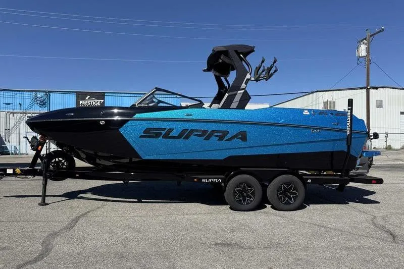 Slide: The Image of 2026 Supra SL boat in blue on a trailer, parked outdoors. - 10