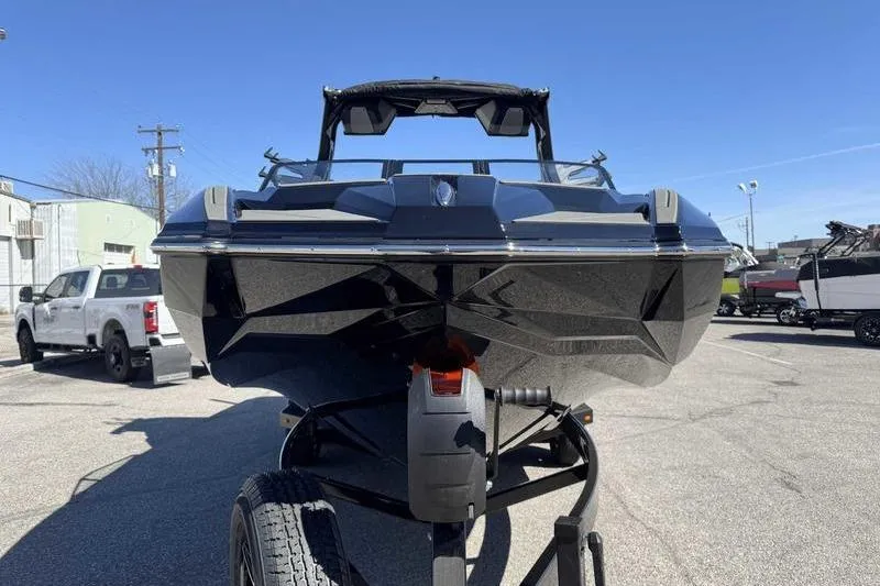 Slide: The Image of 2026 Supra SL boat on trailer, sleek black design, parked outdoors under clear blue sky. - 15