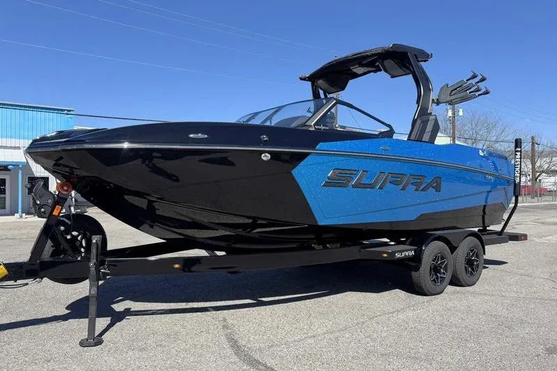 Slide: The Image of 2026 Supra SL boat in blue and black on a trailer, parked outdoors. - 8