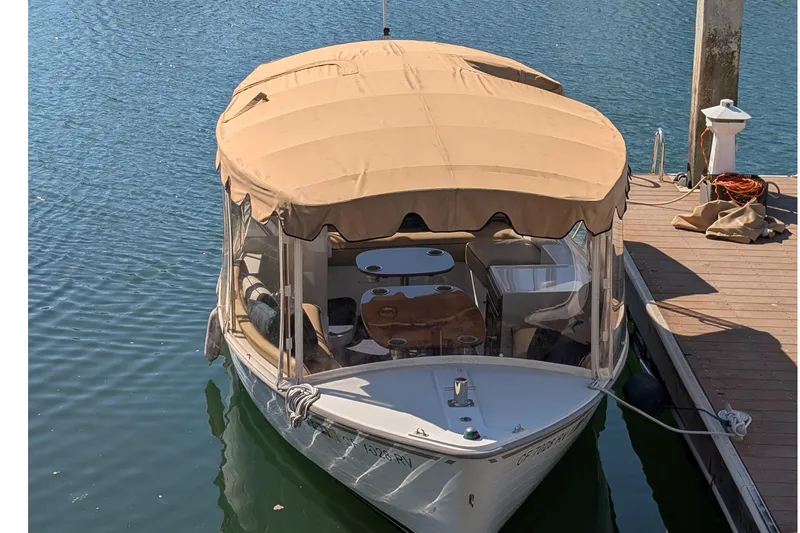 Slide: The Image of 2013 Duffy Snug Harbor 18 electric boat docked with beige canopy. - 10