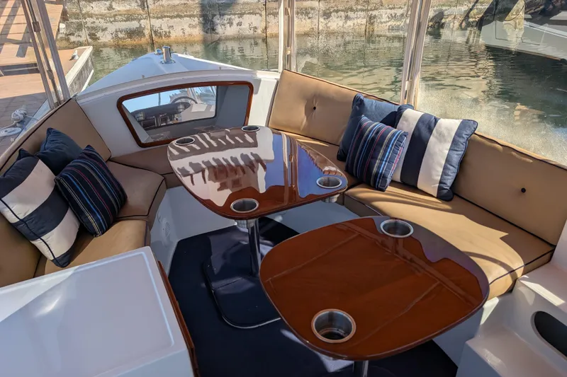 Slide: The Image of Interior of 2013 Duffy Snug Harbor 18 boat with cushioned seating and wooden tables. - 7