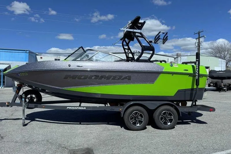 The Image of 2021 Moomba Mondo boat on trailer, vibrant green and gray design, parked outdoors. - 0