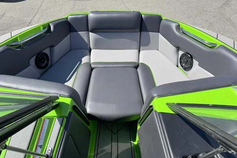 Slide: The Image of 2021 Moomba Mondo boat interior with gray and green seating, featuring built-in speakers. - 10
