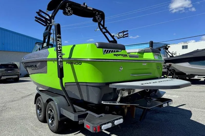 Slide: The Image of 2021 Moomba Mondo boat in vibrant green on a trailer, parked outdoors. - 11