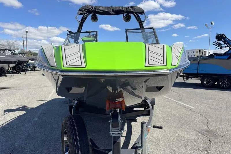 Slide: The Image of 2021 Moomba Mondo boat with vibrant green hull on a trailer under a clear blue sky. - 12