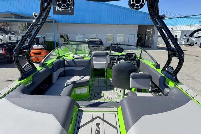 Slide: The Image of 2021 Moomba Mondo boat interior with green and gray seating, parked outdoors. - 13