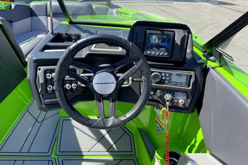 Slide: The Image of 2021 Moomba Mondo boat cockpit with steering wheel and control panel, featuring vibrant green accents. - 7
