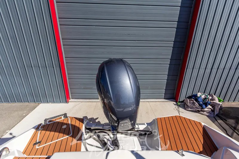 Slide: The Image of 2017 NauticStar 193 SC boat with outboard motor, docked near a metal garage door. - 11