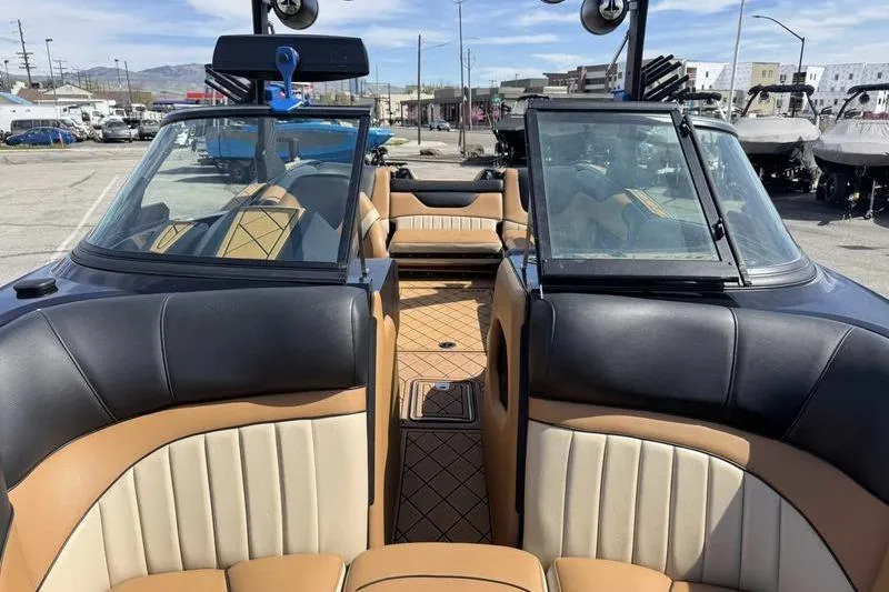 Slide: The Image of 2022 MB Sport B52 boat interior with tan and black seating, docked in a marina. - 8