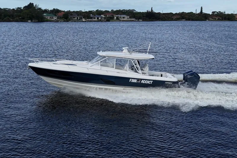 The Image of 2024 Intrepid 41 Valor cruising on a serene lake with scenic shoreline. - 0