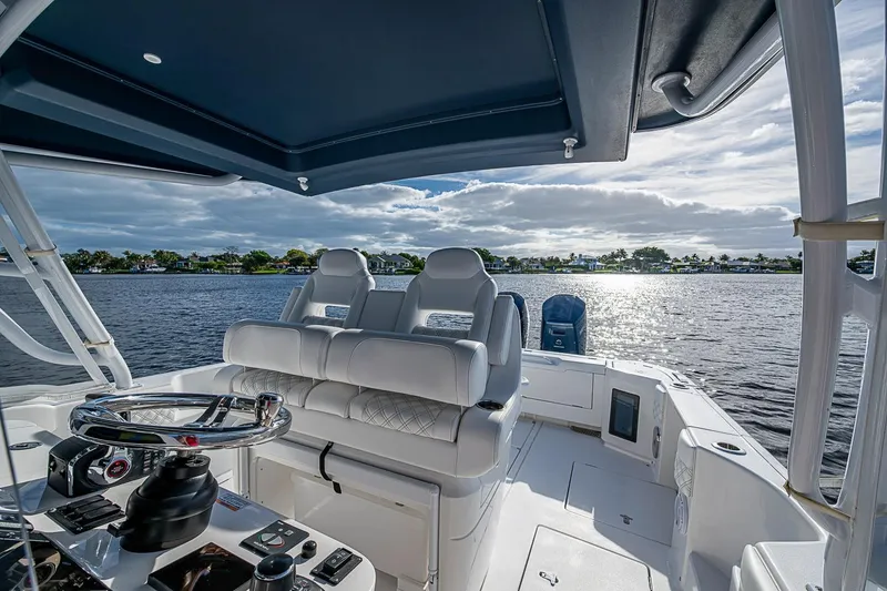 Slide: The Image of 2024 Intrepid 41 Valor boat interior with helm, luxurious seating, and scenic water view. - 25