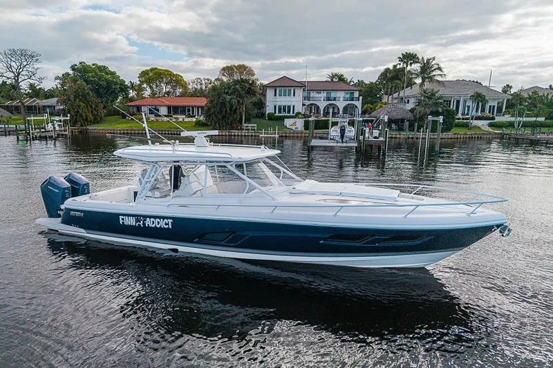 Slide: The Image of 2024 Intrepid 41 Valor boat docked near waterfront homes, showcasing sleek design and powerful engines. - 6