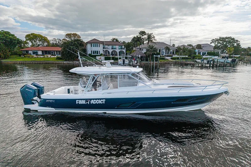 Slide: The Image of 2024 Intrepid 41 Valor boat on calm water near luxury waterfront homes. - 7