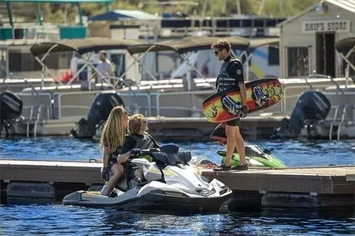 Slide: The Image of People enjoying a Kawasaki ULTRA 160LX jet ski at a marina, with wakeboards nearby. - 2