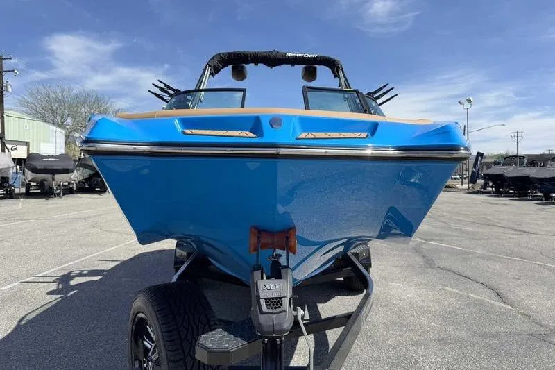 Slide: The Image of 2022 MasterCraft XT22 boat in vibrant blue on a trailer, parked outdoors. - 11
