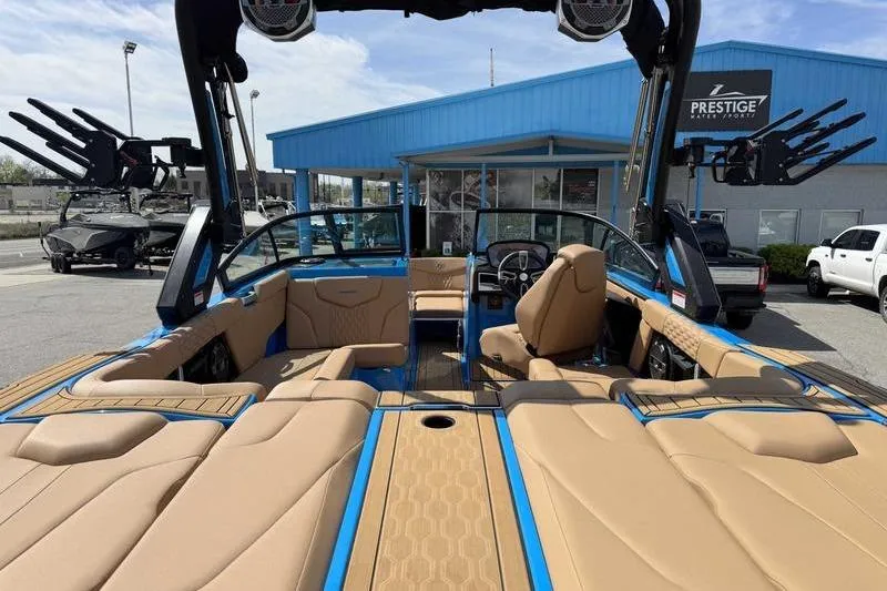 Slide: The Image of 2022 MasterCraft XT22 boat with tan interior and blue accents at a dealership. - 5