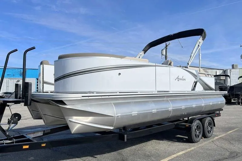 Slide: The Image of 2023 Avalon 2385 25 LSZ QL pontoon boat on trailer, parked outdoors. - 2
