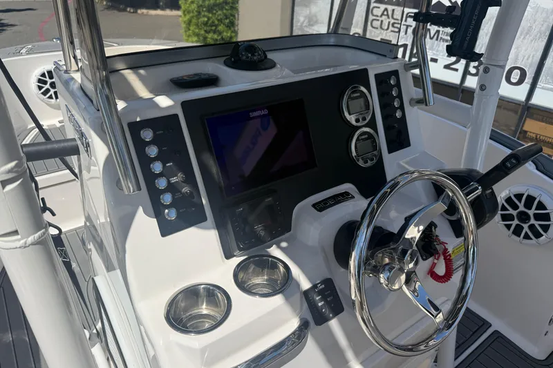 Slide: The Image of 2025 Robalo R180 Center Console boat dashboard with steering wheel and electronic controls. - 16