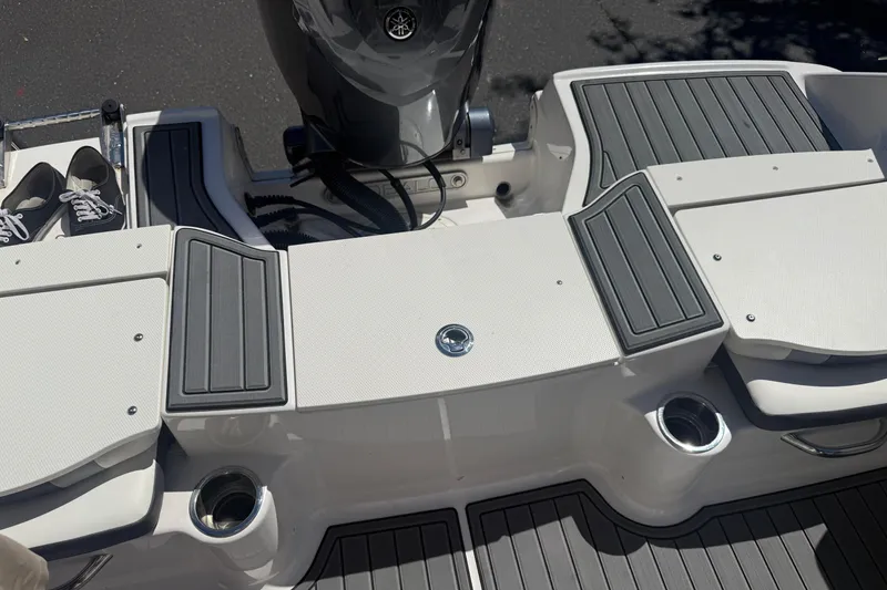 Slide: The Image of 2025 Robalo R180 Center Console boat deck with gray non-slip pads and cup holders. - 28