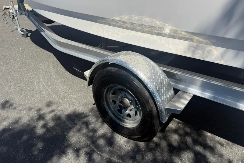 Slide: The Image of Trailer wheel of 2025 Robalo R180 Center Console boat on asphalt. - 9