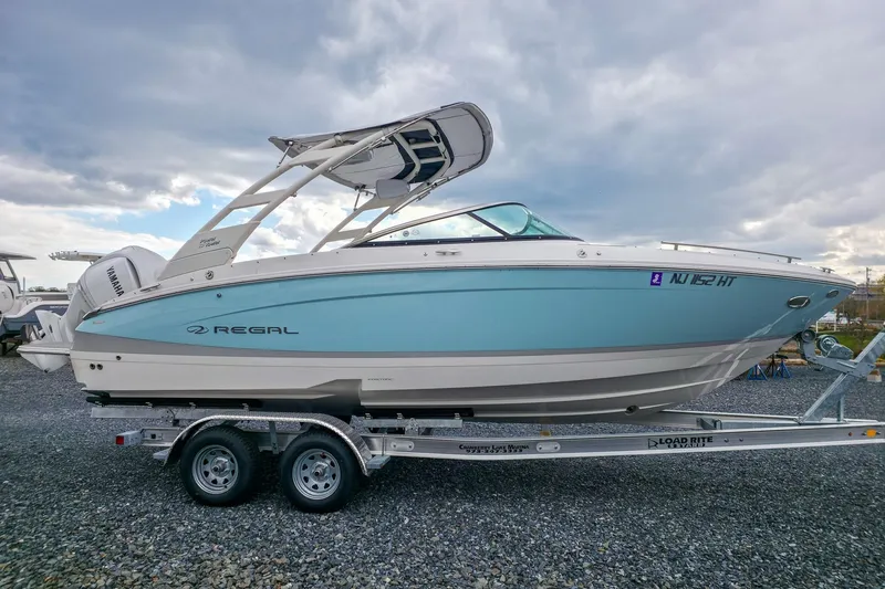 Slide: The Image of 2025 Regal LX4 boat on trailer, side view, under cloudy sky. - 10