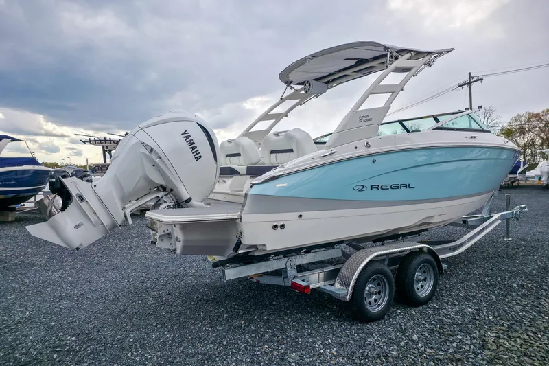 Slide: The Image of 2025 Regal LX4 boat with Yamaha engine on a trailer, parked outdoors. - 11