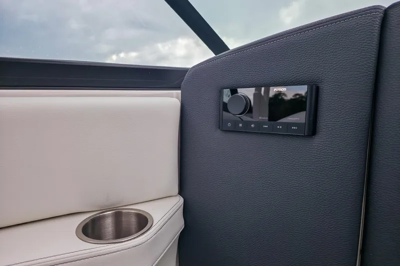 Slide: The Image of Interior of 2025 Regal LX4 boat featuring a Fusion audio system and cup holder. - 23
