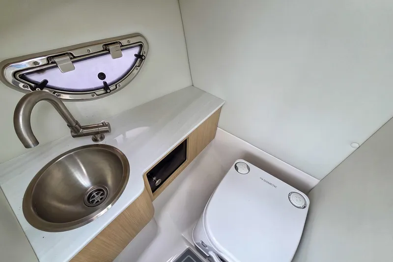 Slide: The Image of Compact bathroom in 2025 Regal LX4 boat with sink, toilet, and porthole window. - 24