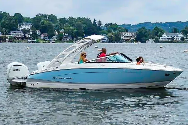 Slide: The Image of 2025 Regal LX4 boat cruising on a scenic lake with passengers onboard. - 4