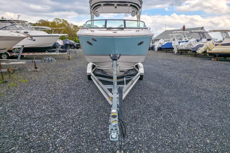 Slide: The Image of 2025 Regal LX4 boat on trailer in a gravel lot, surrounded by other boats. - 8