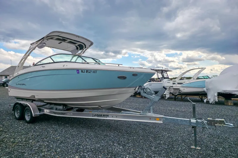Slide: The Image of 2025 Regal LX4 boat on trailer under cloudy sky at marina. - 9