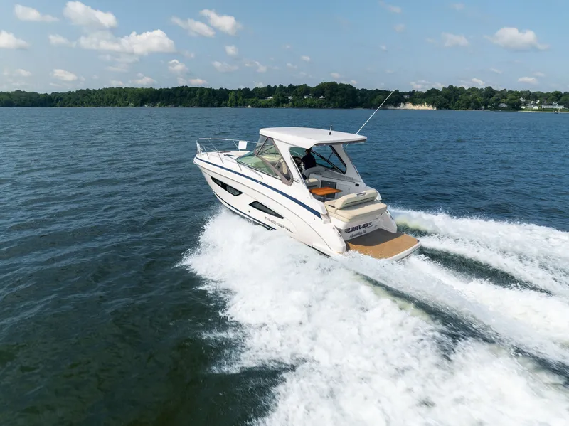 Slide: The Image of 2019 Regal 33 Express cruising swiftly on a lake with a wooded shoreline in the background. - 6