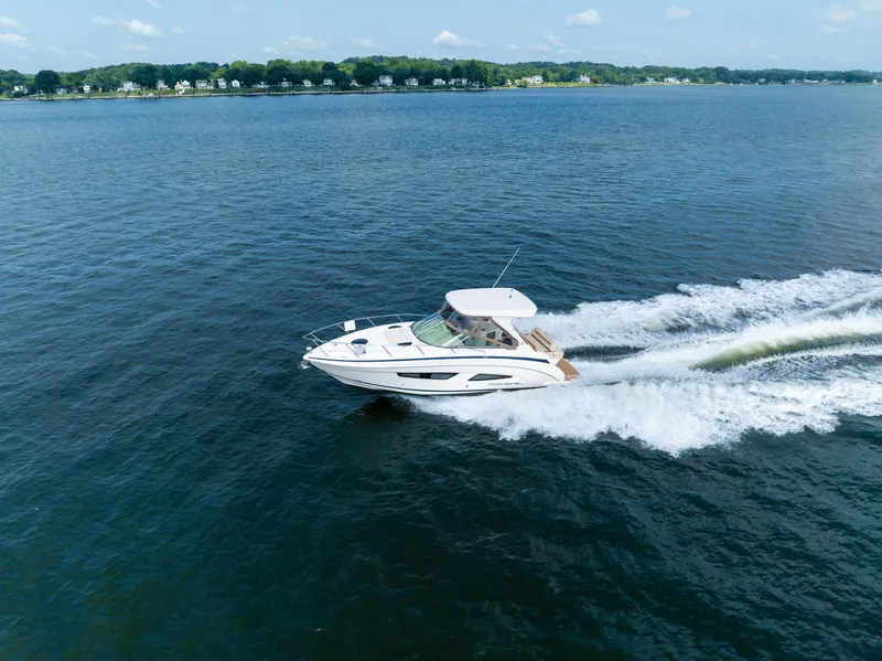 Slide: The Image of A 2019 Regal 33 Express speeds across the water, surrounded by a calm landscape. - 3