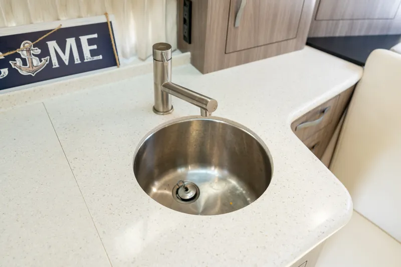 Slide: The Image of A modern stainless steel sink in a sleek kitchenette with light countertops. - 26