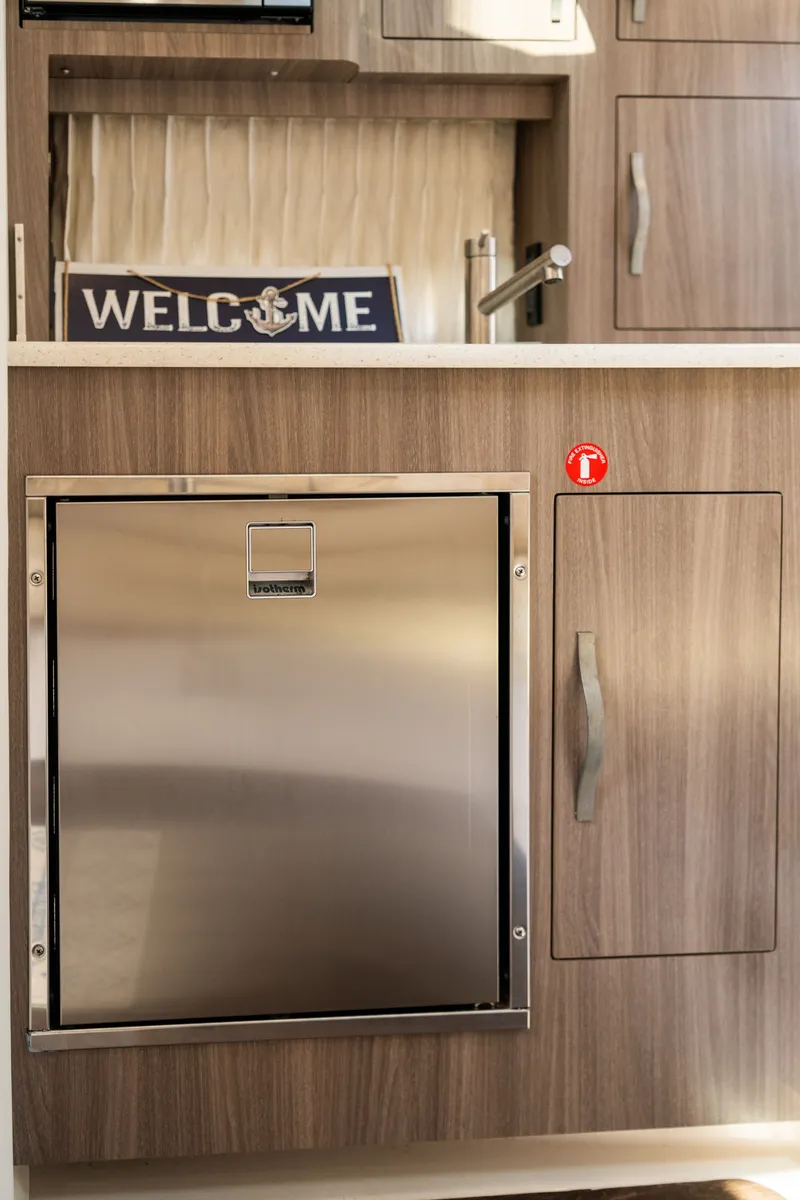 Slide: The Image of Interior of the 2019 Regal 33 Express with wood cabinets and a "Welcome" sign. - 22