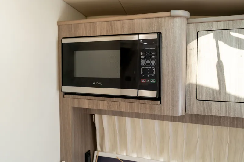 Slide: The Image of A microwave is installed in a Regal boat, surrounded by wood paneling. - 25