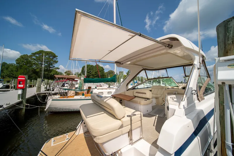 Slide: The Image of The image shows a 2019 Regal 33 Express docked. It features an open cockpit with beige seating and a retractable sunshade. Other boats and a partly cloudy sky are visible in the background. - 40