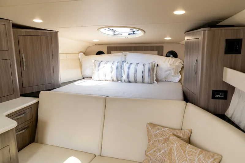 Slide: The Image of Cabin of the 2019 Regal 33 Express with a double bed, pillows, and wooden cabinets. - 28