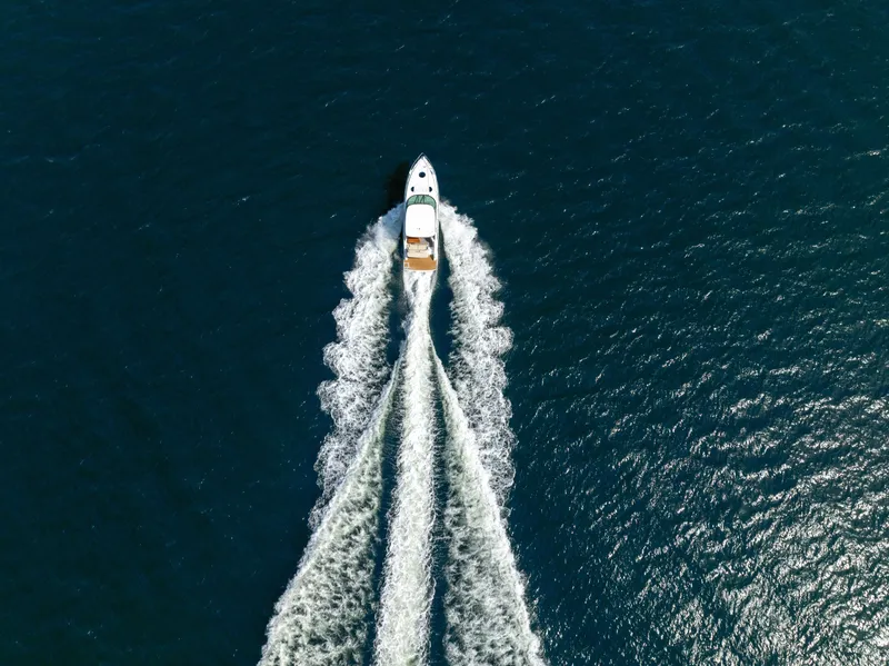 Slide: The Image of Aerial view of a white boat cruising on open water, leaving a long wake behind. - 1