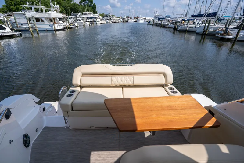 Slide: The Image of The image shows the stern of a 2019 Regal 33 Express with a wooden table and beige seating. - 13