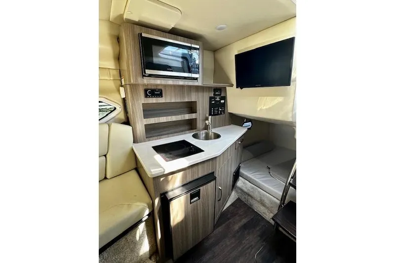 Slide: The Image of 2022 Regal 26 XO boat interior with kitchenette, microwave, sink, and TV. - 11