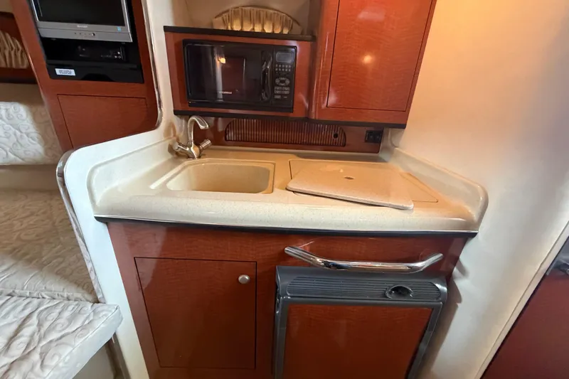 Slide: The Image of 2005 Sea Ray Sundancer 280 galley with sink, microwave, and compact fridge. - 20