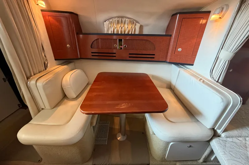 Slide: The Image of 2005 Sea Ray Sundancer 280 interior with wooden table, cushioned seating, and elegant cabinetry. - 23